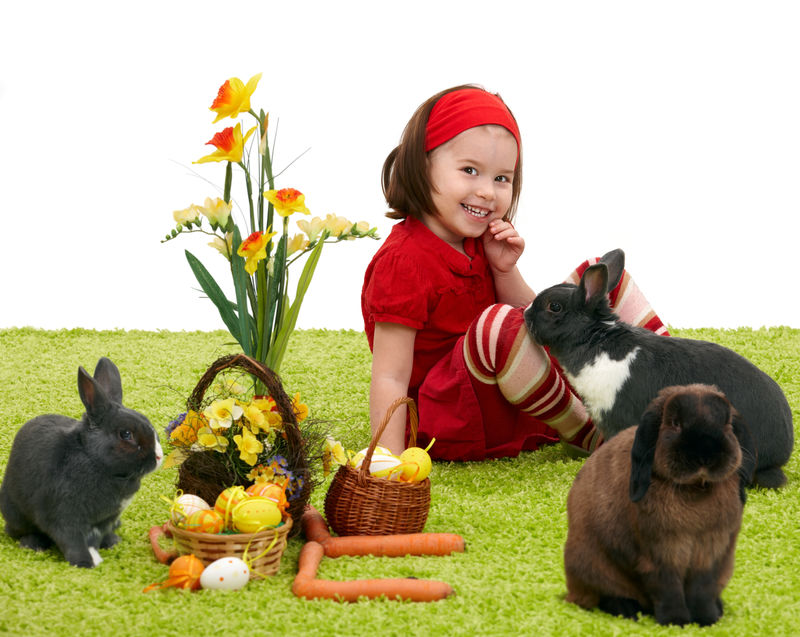 复活节图片：微笑的小女孩和绿色地毯上的复活节兔子