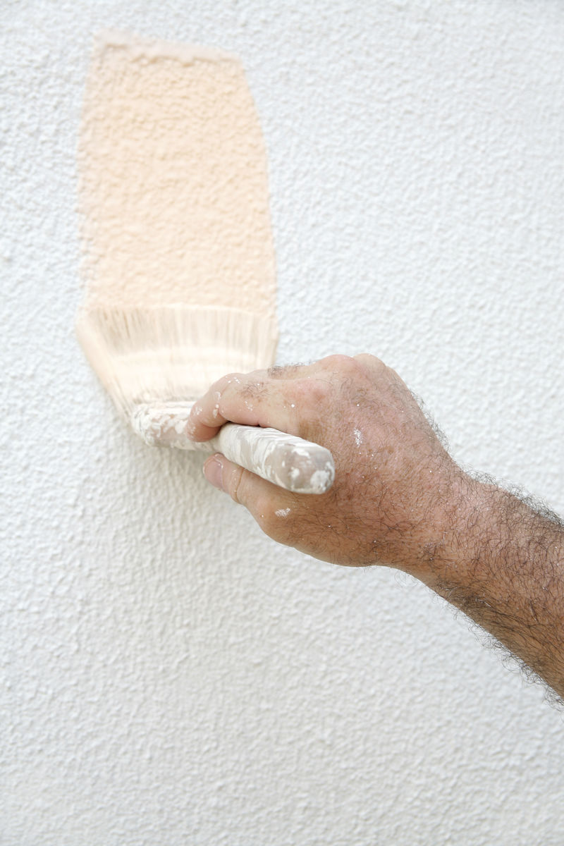 一个男人手里拿着一把漆刷-正在油漆房子