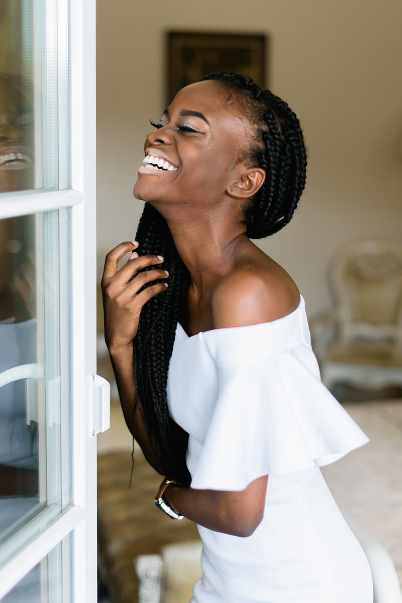 漂亮的非洲女人站在贵宾豪华酒店的敞开的门前微笑着她穿着一件优雅的白色连衣裙