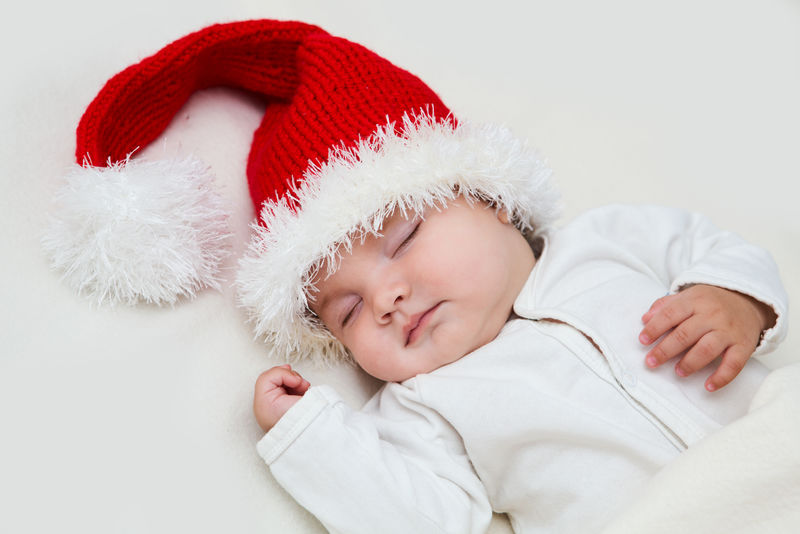 白色毛毯上戴圣诞老人帽的小婴儿照片