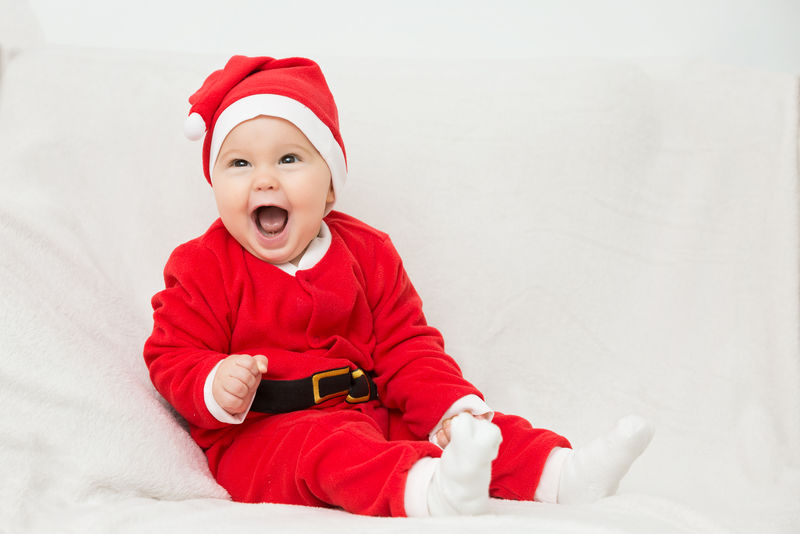 七个月大的小女孩穿着圣诞老人的衣服坐着