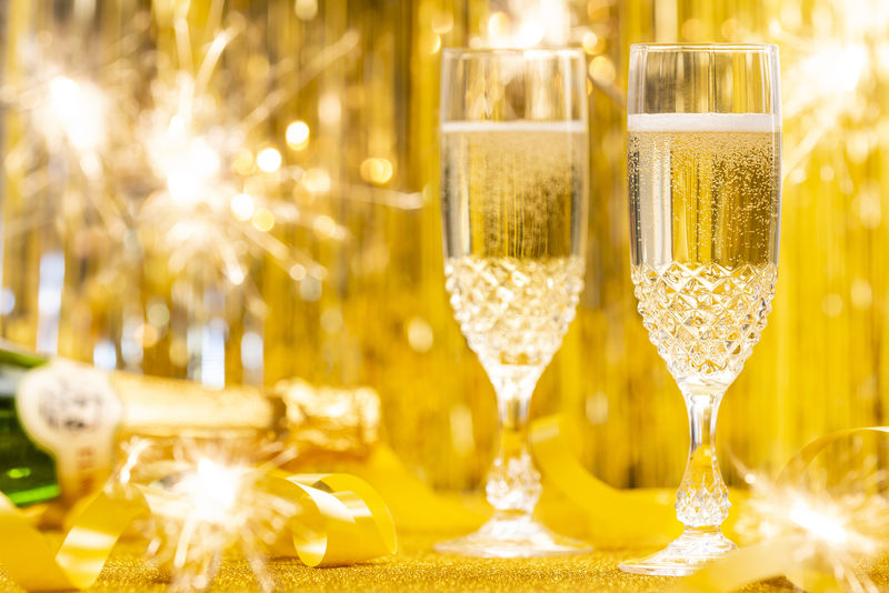 满是香槟和金光闪闪的背景的玻璃杯