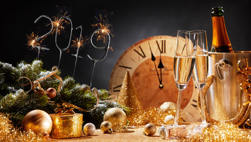 2019年新年前夜派对背景是香槟装饰品和倒计时至午夜的时钟