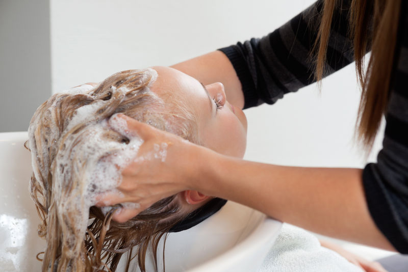 美容师在美容水疗中心洗掉女人头发上的洗发水
