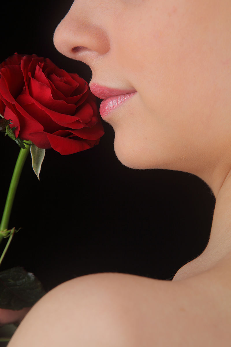 抱着闻着红玫瑰的年轻漂亮女人