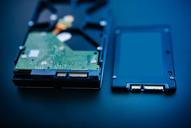 硬盘旁边的SSD磁盘（固态驱动器）蓝色技术背景-倾斜移动镜头用于强调硬盘的中心-并强调他们的连接
