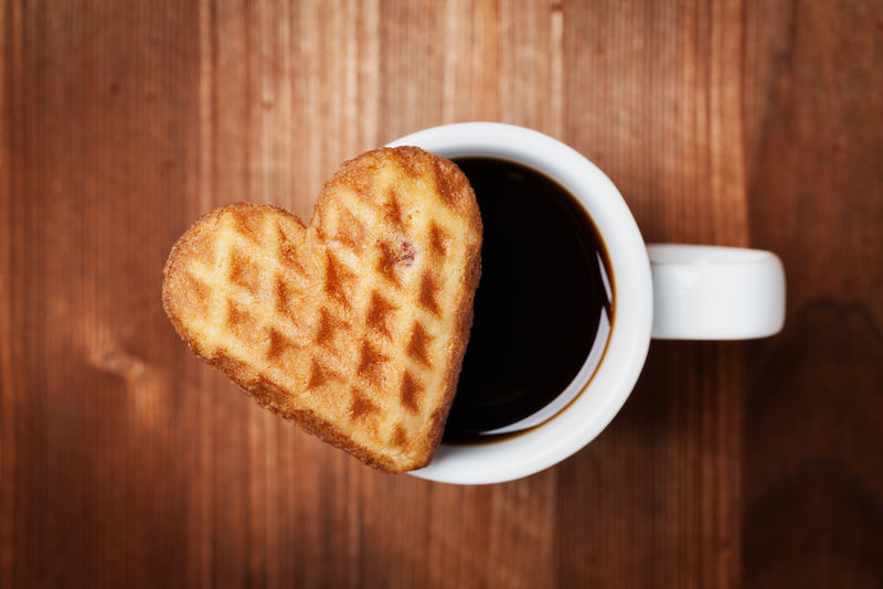 巧克力饼干形状的心与咖啡杯在木制背景情人节顶视图