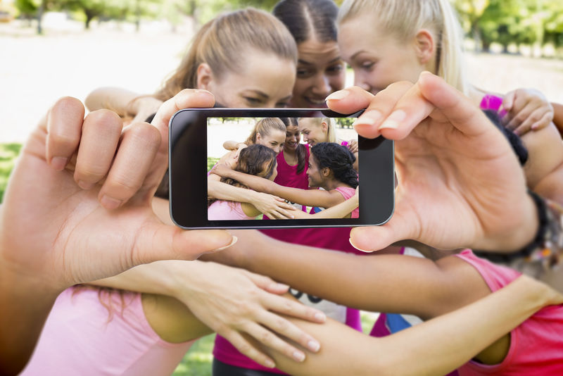 手持智能手机的合成图像显示乳腺癌活动家的照片
