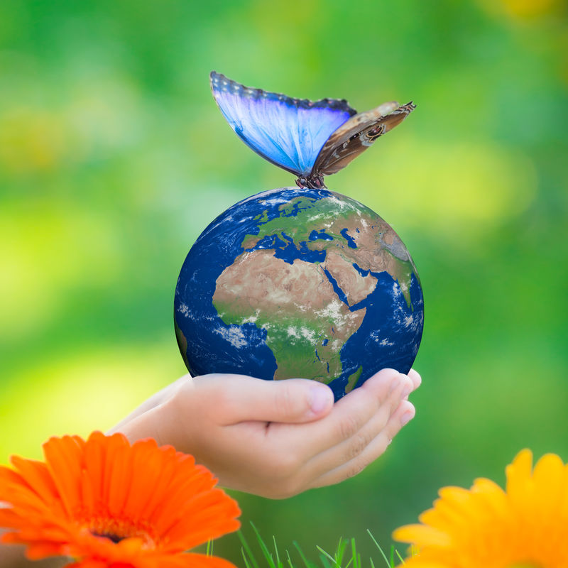 在绿色模糊的背景下-手里拿着蓝色蝴蝶的孩子抱着地球-地球日-春假概念-NASA提供的这张图片的元素