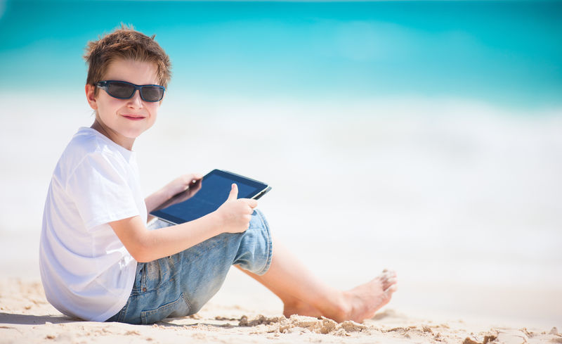 海滩上带平板电脑的男孩