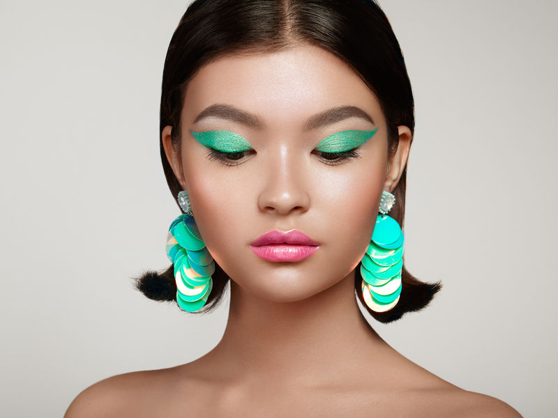 漂亮的韩国女人戴着大绿松石耳环完美的化妆和优雅的发型绿松石配箭和粉红唇膏