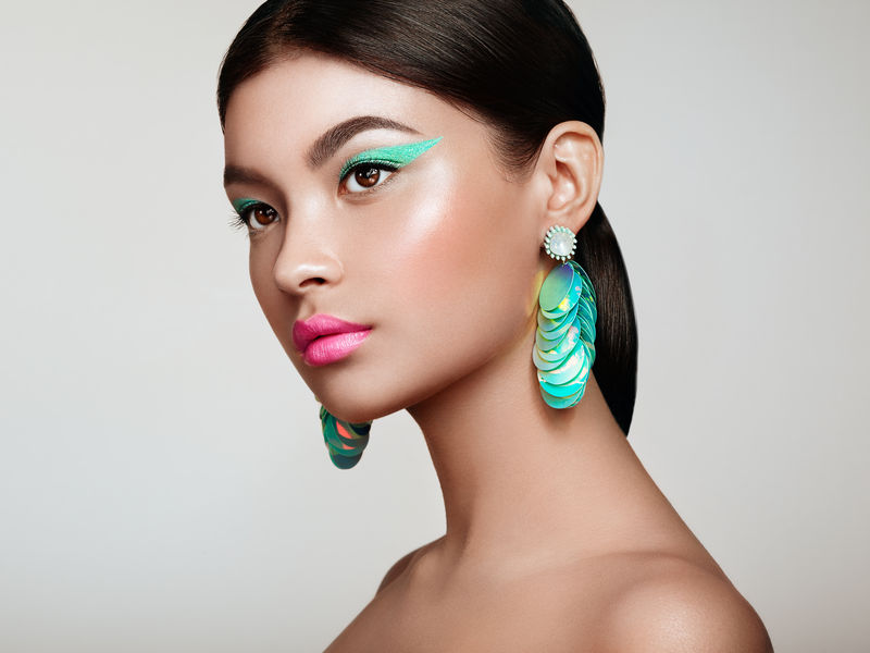 漂亮的韩国女人戴着大绿松石耳环完美的化妆和优雅的发型绿松石配箭和粉红唇膏