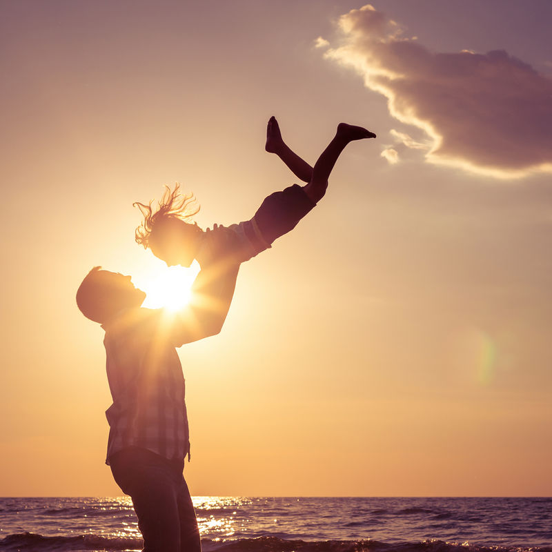 日落时分-爸爸和儿子在海滩上玩耍-友好家庭概念