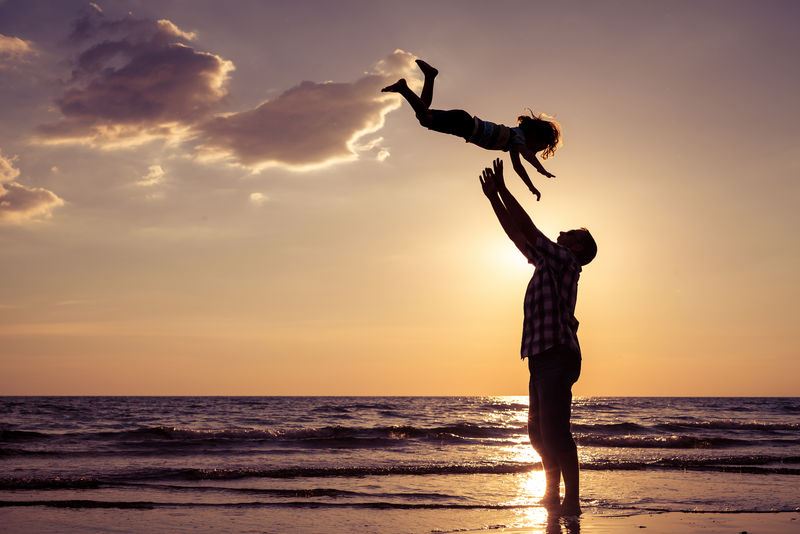 日落时分-爸爸和儿子在海滩上玩耍-友好家庭概念