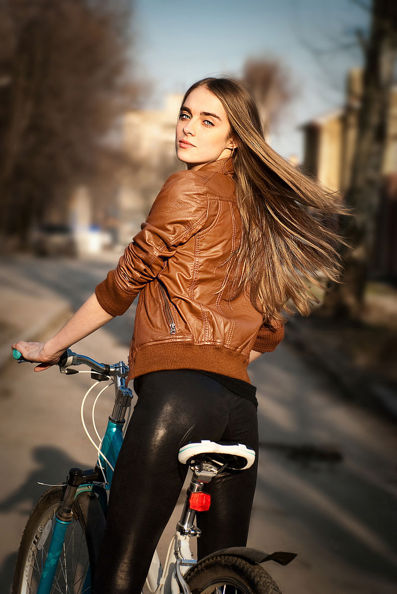 城市道路上骑自行车的漂亮年轻女子的画像