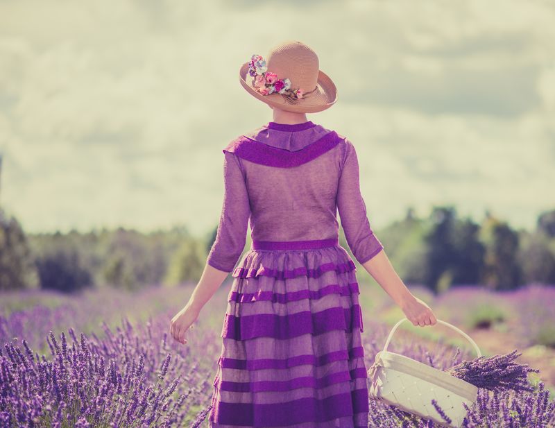 穿着紫色连衣裙戴着花篮的女人在薰衣草地