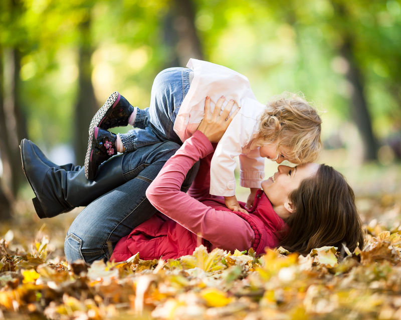带孩子的女人在秋天公园玩得开心