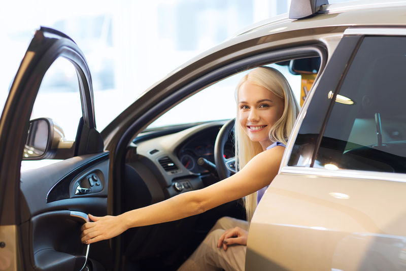 汽车生意汽车销售消费交通和人们的观念——坐在车里或开车的快乐女人