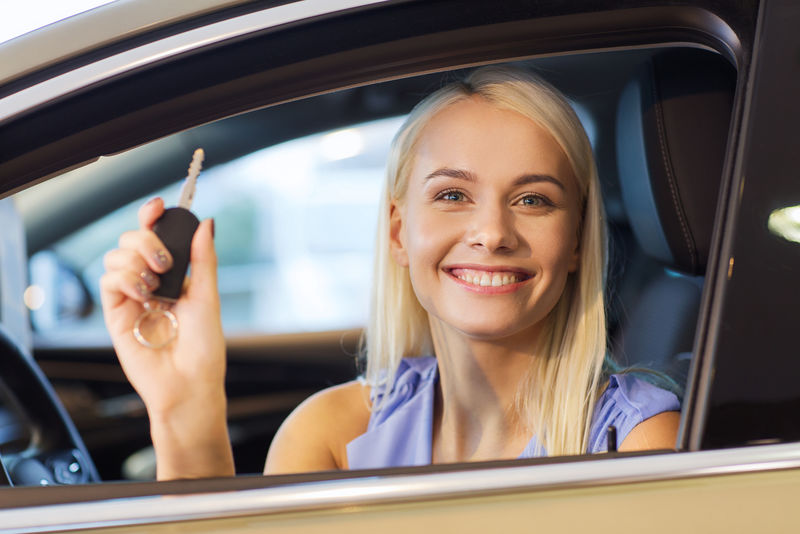 汽车生意汽车销售消费和人的观念——从汽车展或沙龙的经销商那里拿车钥匙的快乐女人