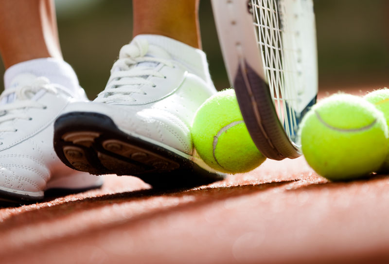 靠近网球拍和球的运动女孩的腿