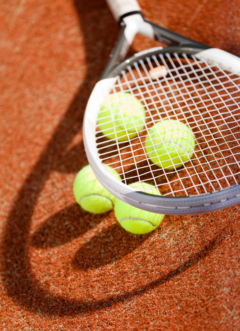 网球拍和粘土网球场上的球的特写镜头
