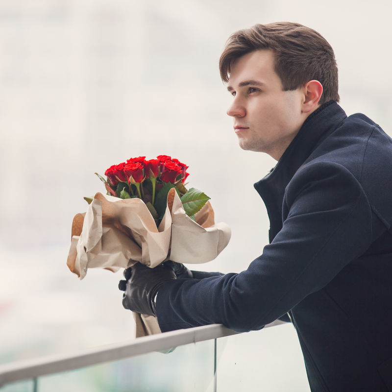 在等他的女朋友拿着一束花的英俊年轻人