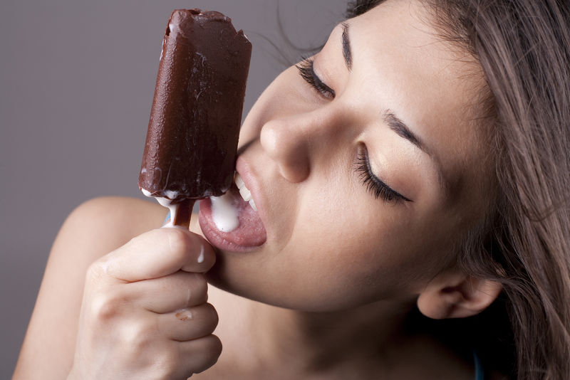 性感的黑发女人舔巧克力冰淇淋