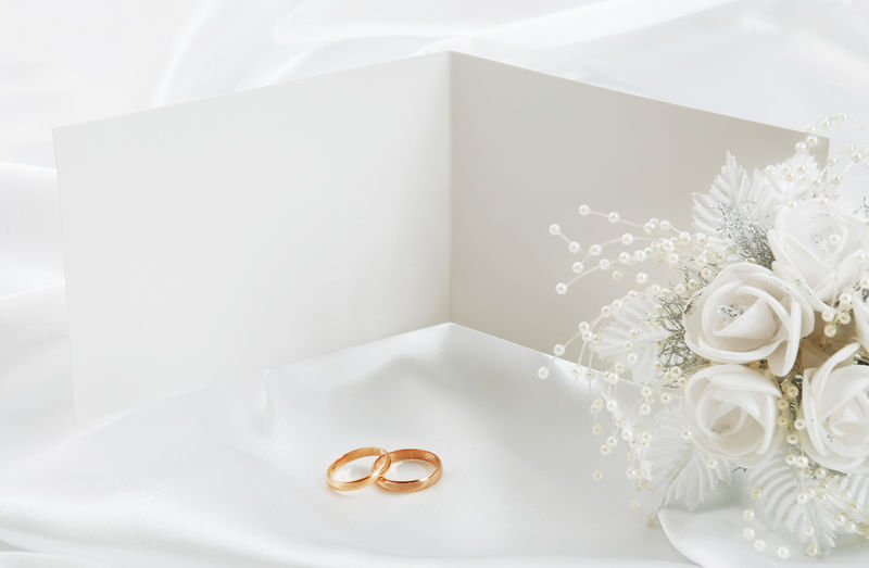 有结婚戒指和白底新娘花束的婚礼请柬