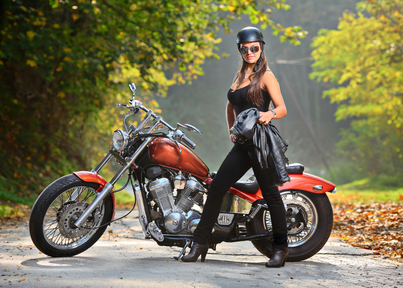骑摩托车的女孩站在摩托车旁边