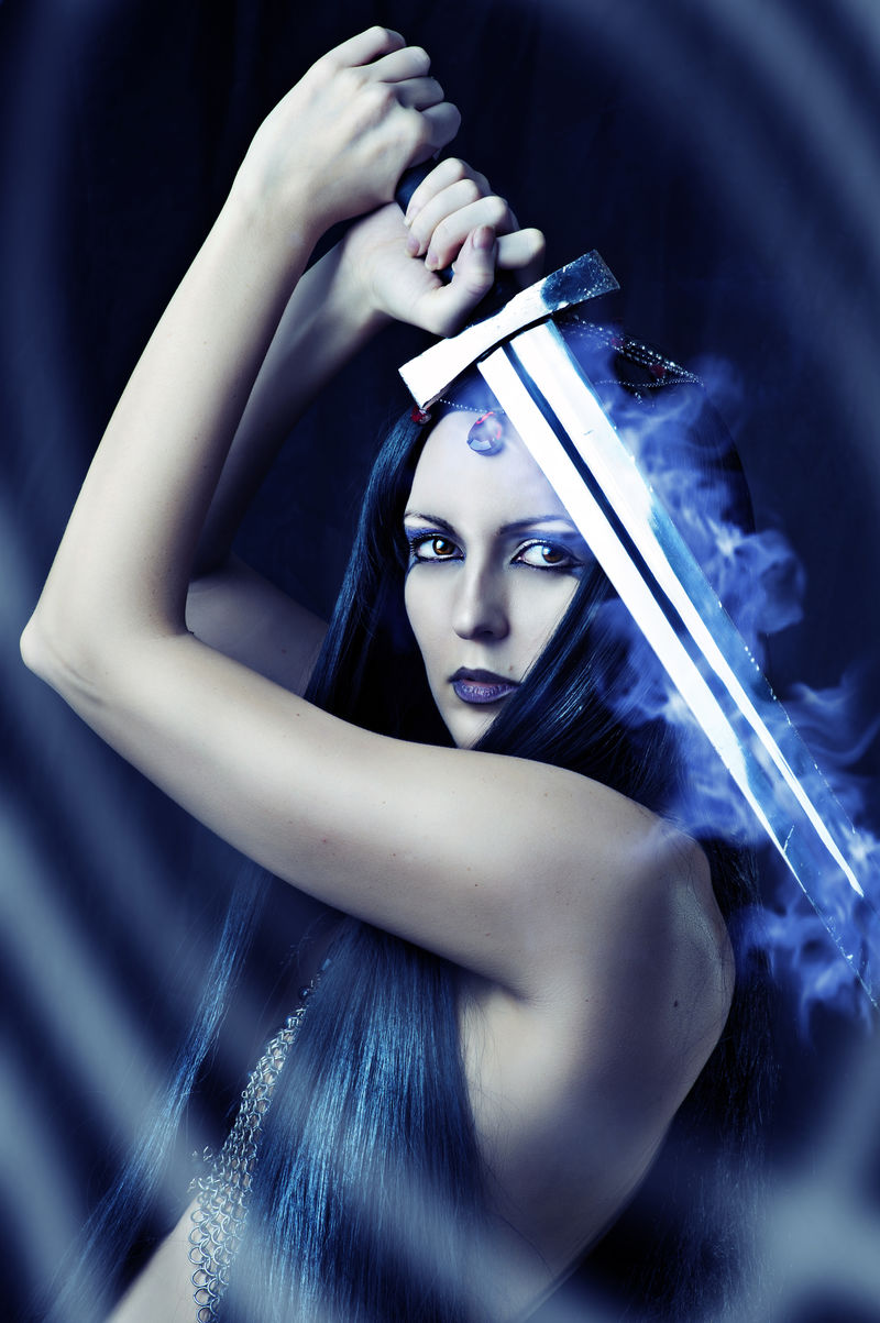 年轻性感的女战士手拿蓝色火剑-留着健康的黑发