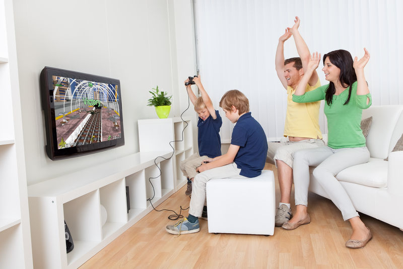 在家玩电子游戏玩得开心的年轻家庭