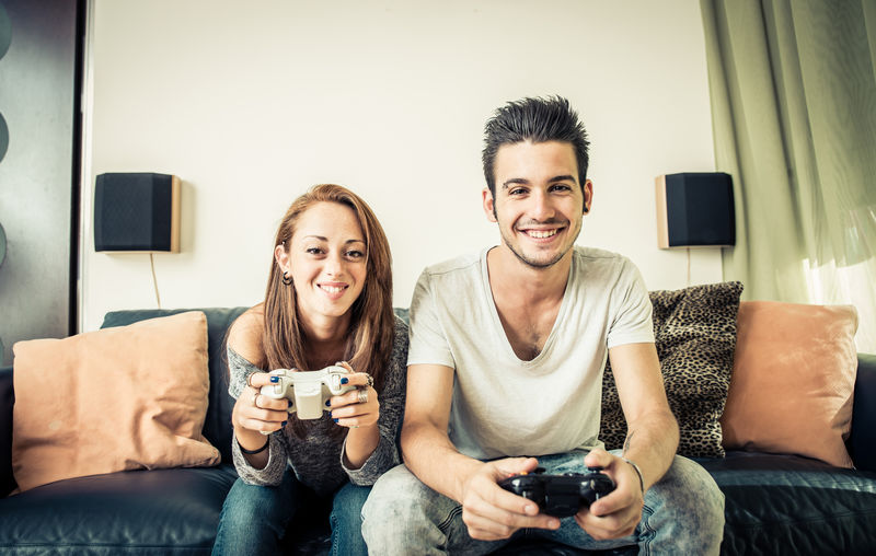 年轻夫妇在客厅玩电子游戏-家庭娱乐概念