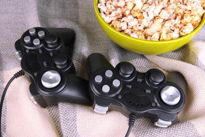 黑色游戏控制器和带有彩色格子背景的爆米花碗