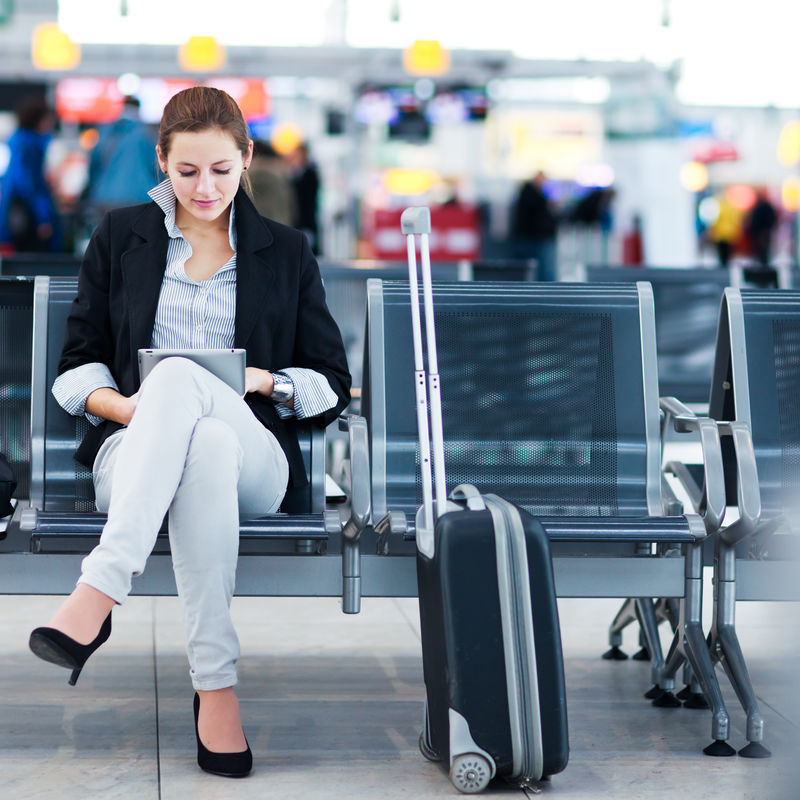 年轻的女乘客在机场用她的平板电脑