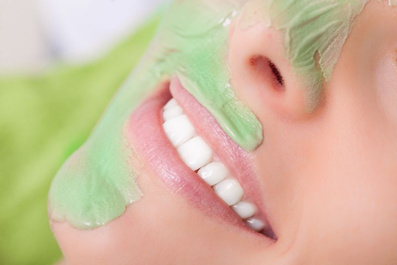 美容治疗理念-在水疗沙龙放松的女人-化妆师在女性脸上涂粘土面膜-身体护理健康的生活方式
