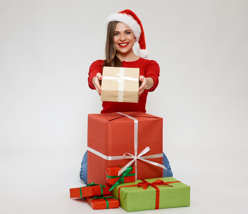 圣诞风格的幸福女人带着礼物坐在地板上的肖像