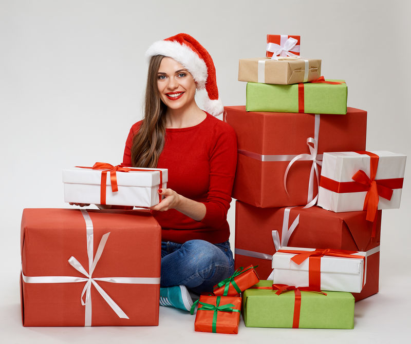 坐在地板上微笑着的女人-带着大礼盒-戴着圣诞帽的独立画像