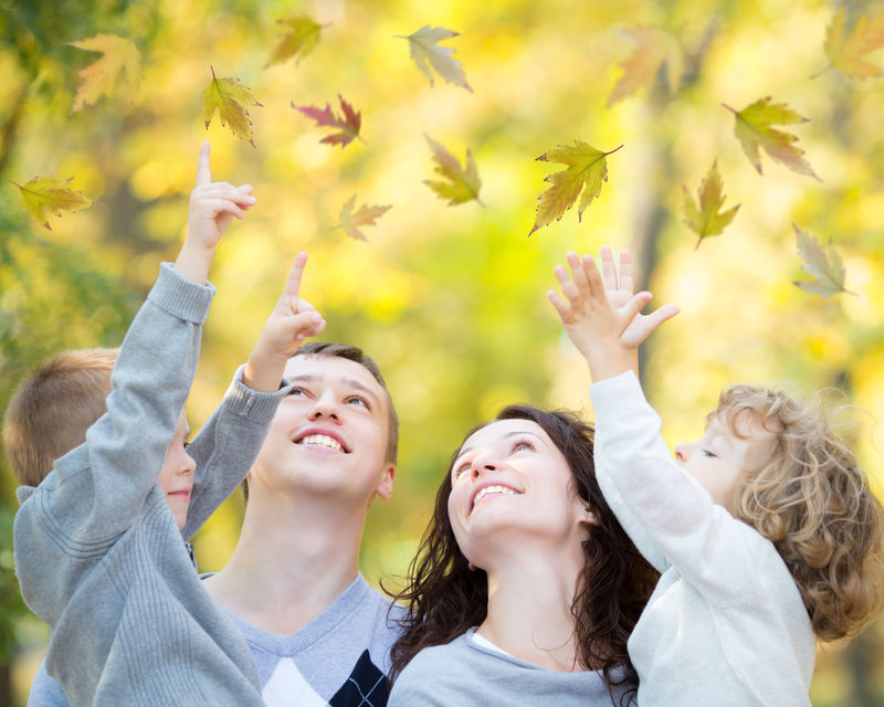 秋天在户外公园里快乐的家庭-在树叶模糊的背景下玩耍