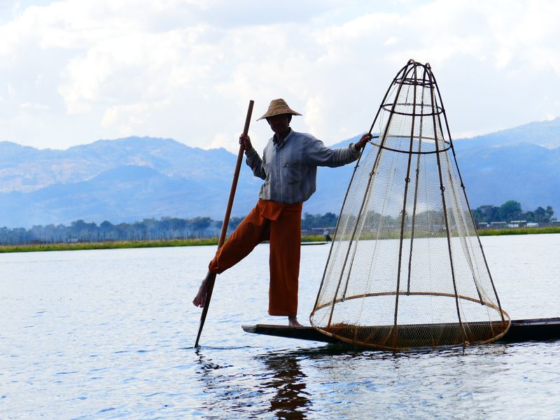 缅甸伊勒湖——大约2014年12月：缅甸伊勒湖-渔民在船上展示如何用传统方法用手工网捕鱼