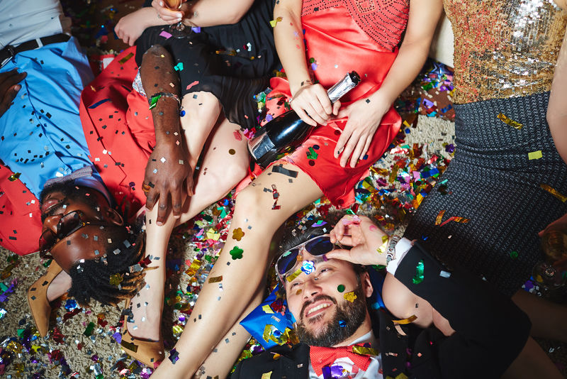 醉醺醺的多朋友在一起庆祝节日的同时，在地板上用五彩的彩纸放松。
