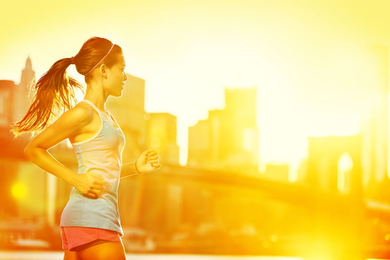 跑步的女人-跑步者在阳光明媚的阳光下慢跑-纽约境外女性健身模式训练——以天际线和布鲁克林大桥为背景