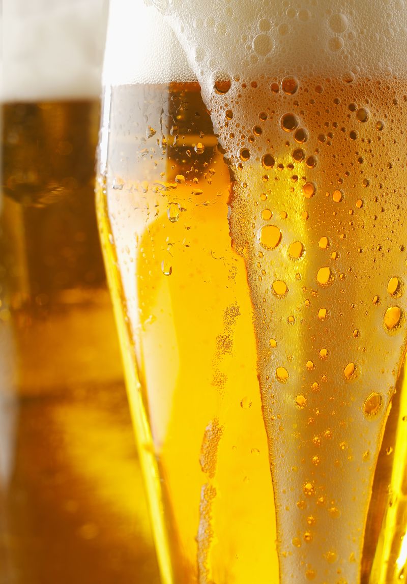 特写一个充满泡沫的金色啤酒或啤酒-液体从玻璃外面流下-修剪过的图像