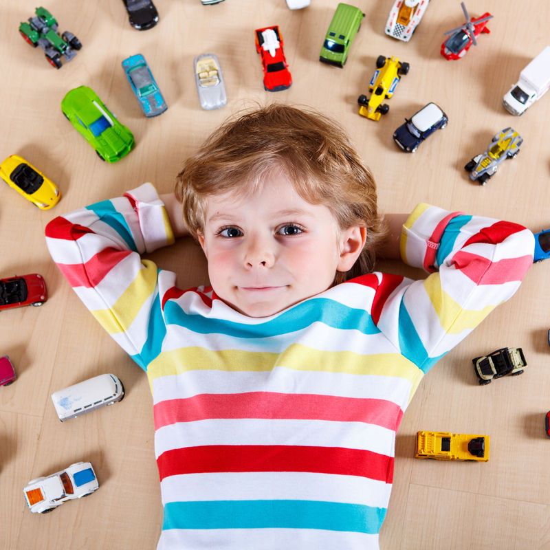 小金发小孩在室内玩很多玩具车-男孩穿着彩色衬衫-玩得很开心