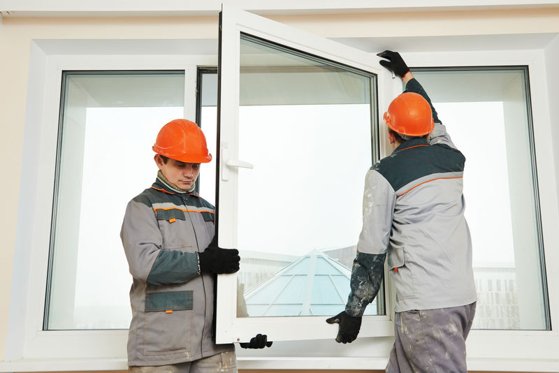两名男性工业建筑工人在安装窗户