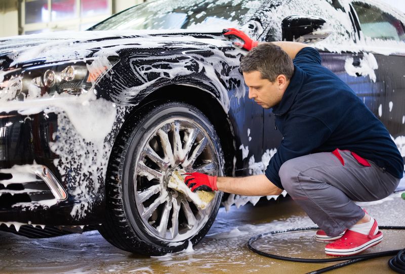 男工人在洗车机上清洗汽车和X27；S合金车轮