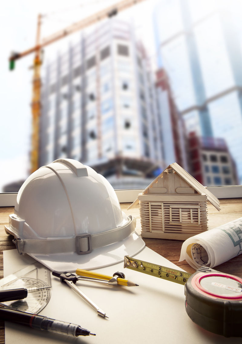工程师工作台安全帽蓝图和施工设备-建筑起重机施工背景-用于房地产和土地开发主题