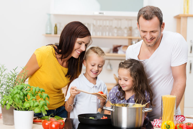 快乐的年轻家庭-妈妈-爸爸和两个孩子一起在厨房做饭-一起准备意大利面