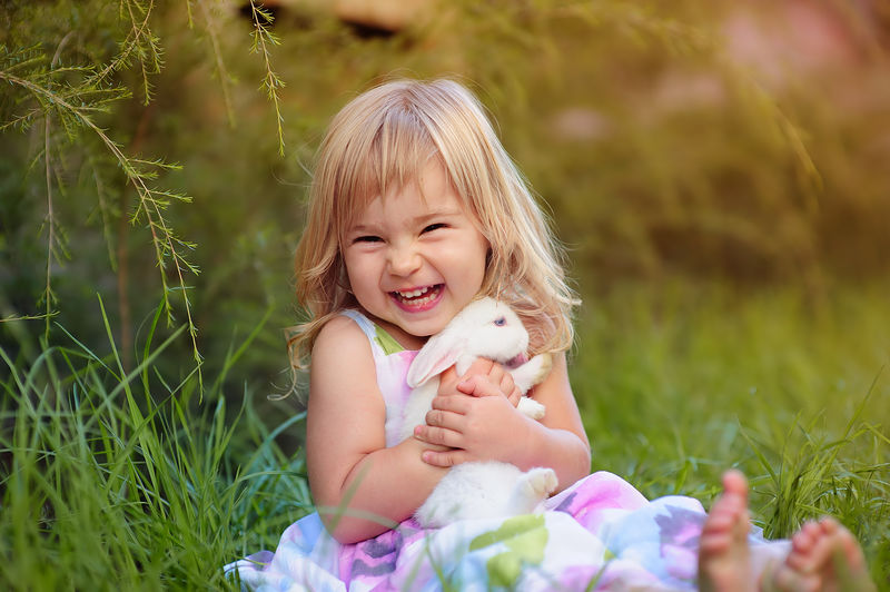 可爱的小女孩和兔子在绿草背景下过复活节