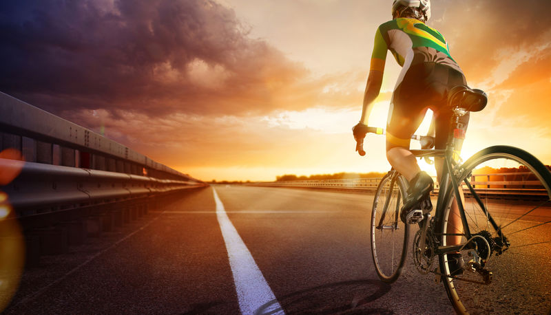 骑自行车的人在通往日落的路上骑自行车