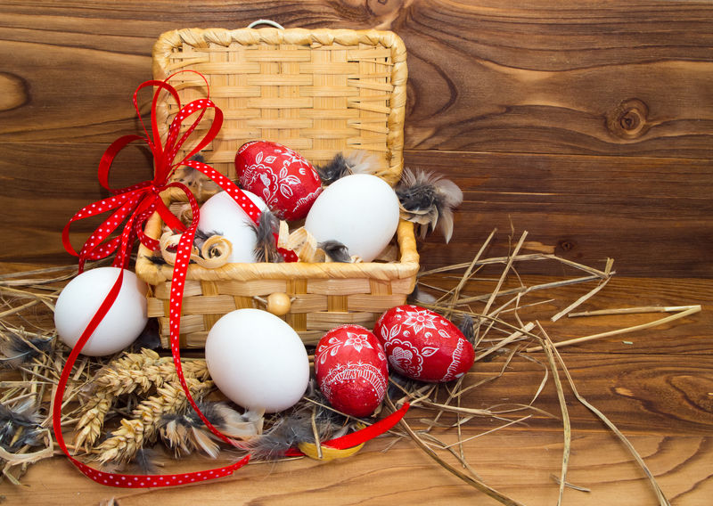 鸡肉和复活节彩蛋放在木制背景的篮子里